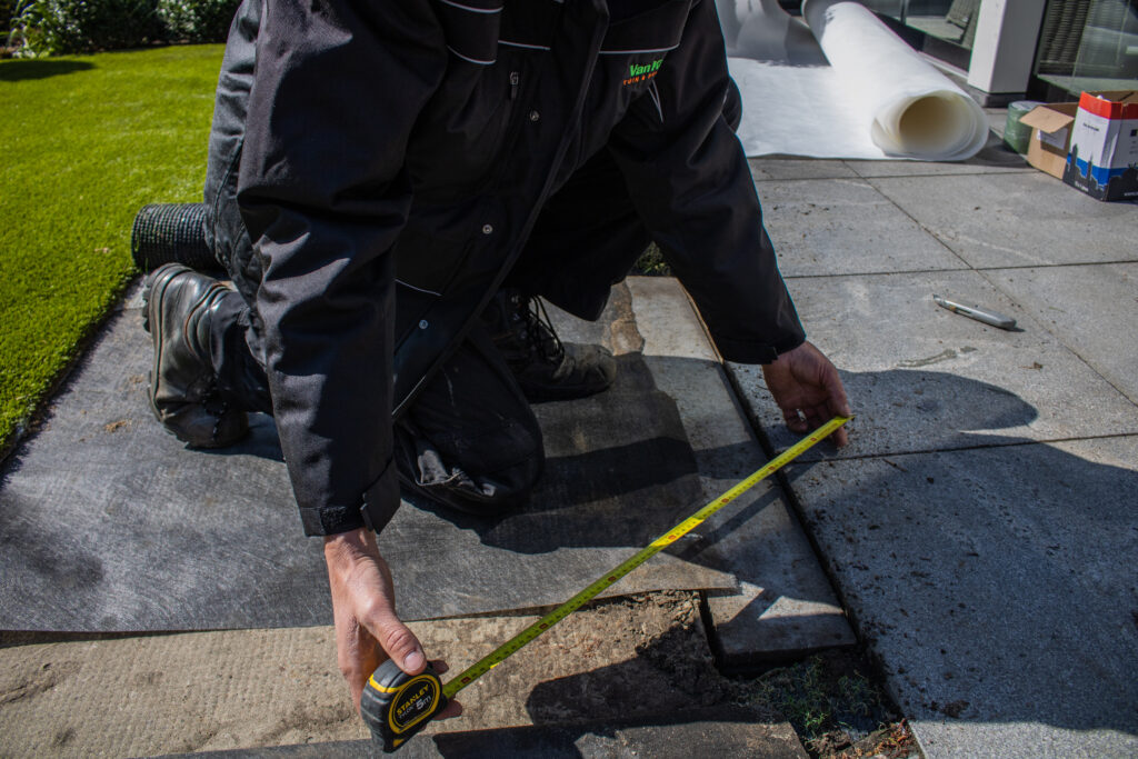 Het opmeten van de tuin om te weten hoeveel kunstgras nodig is.